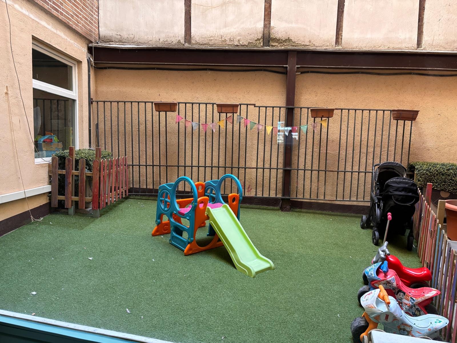Patio exterior con tobogán y guirnalda de banderines
