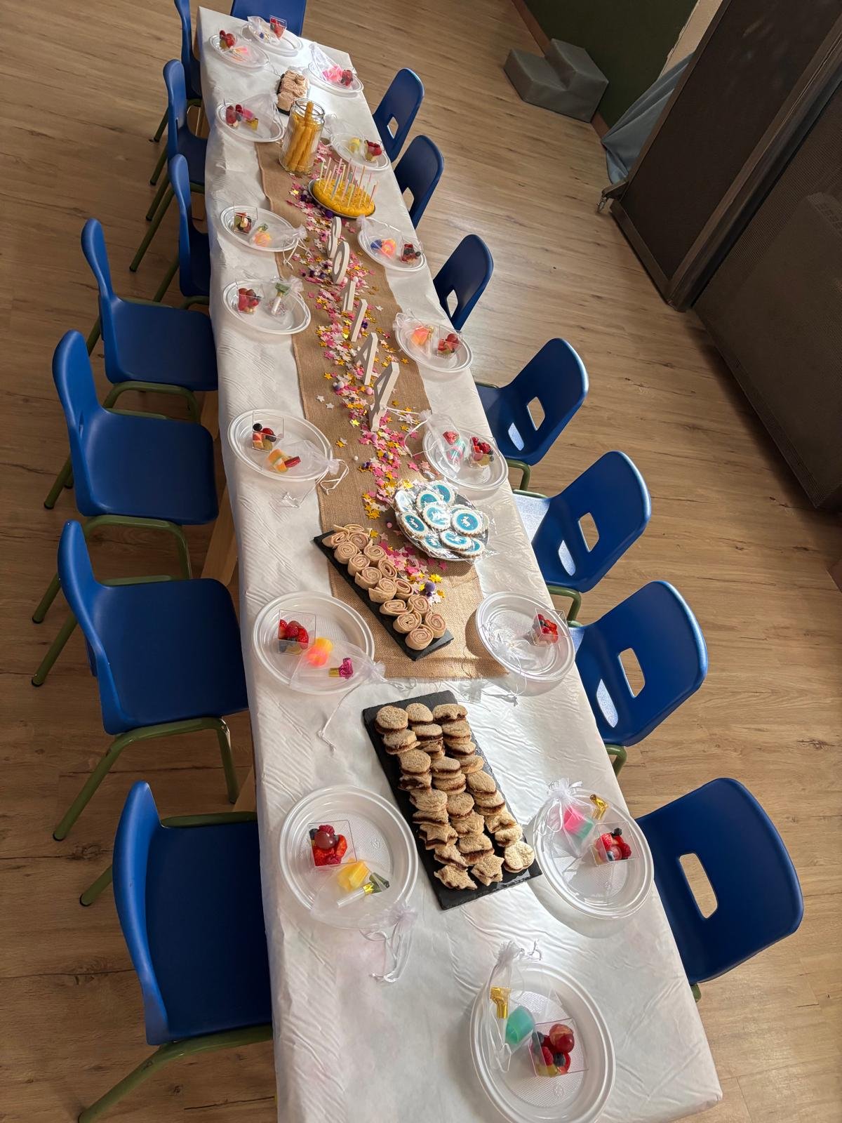 Mesa de cumpleaños con platos, dulces y sillas azules vista desde arriba