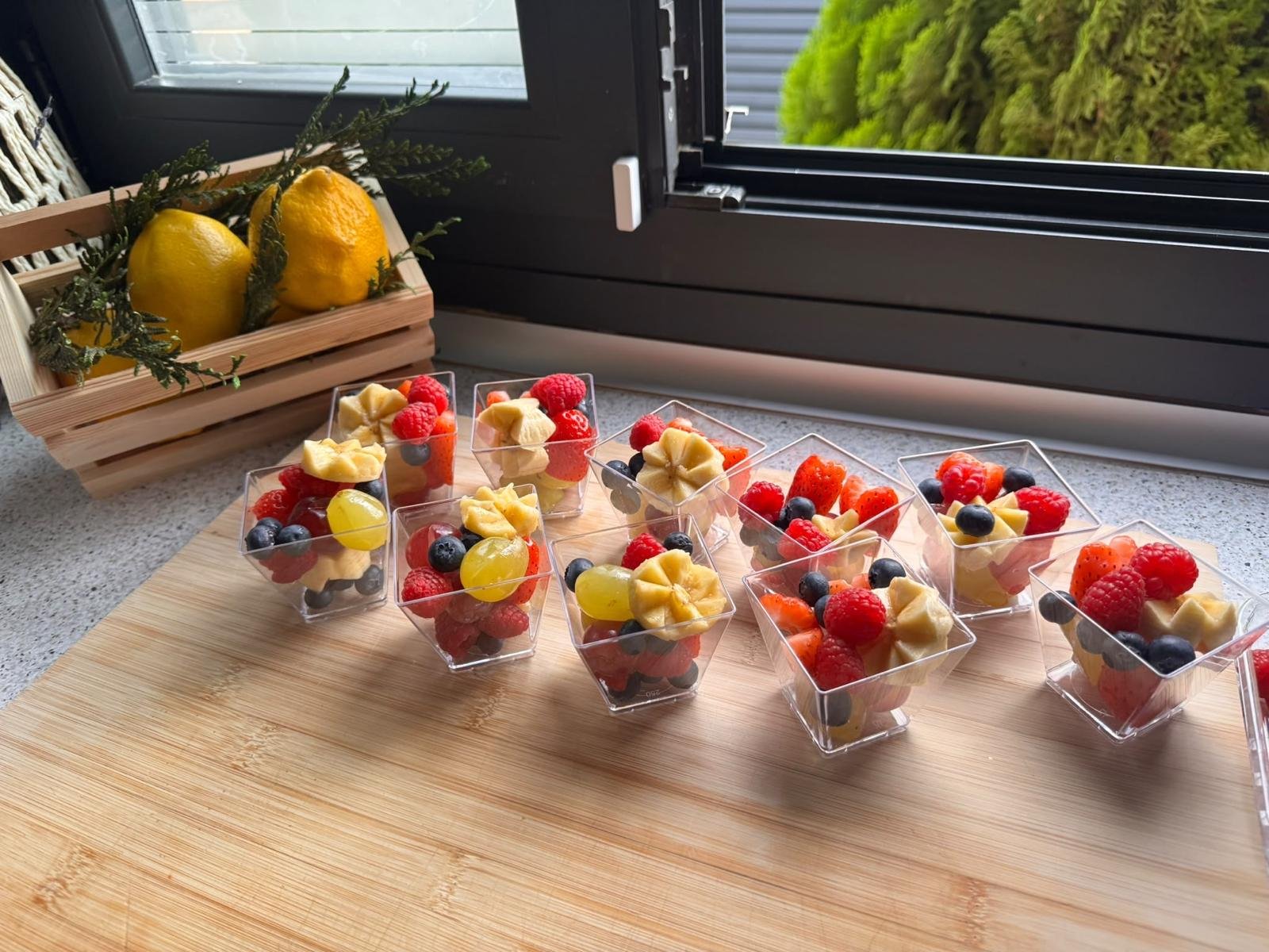 Vasitos de fruta fresca junto a una cesta de limones