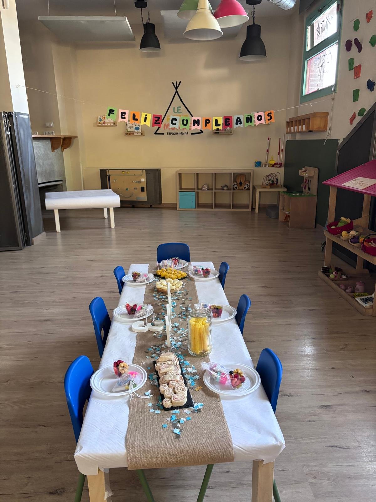 Mesa larga preparada para un cumpleaños con guirnalda de Feliz cumpleaños al fondo
