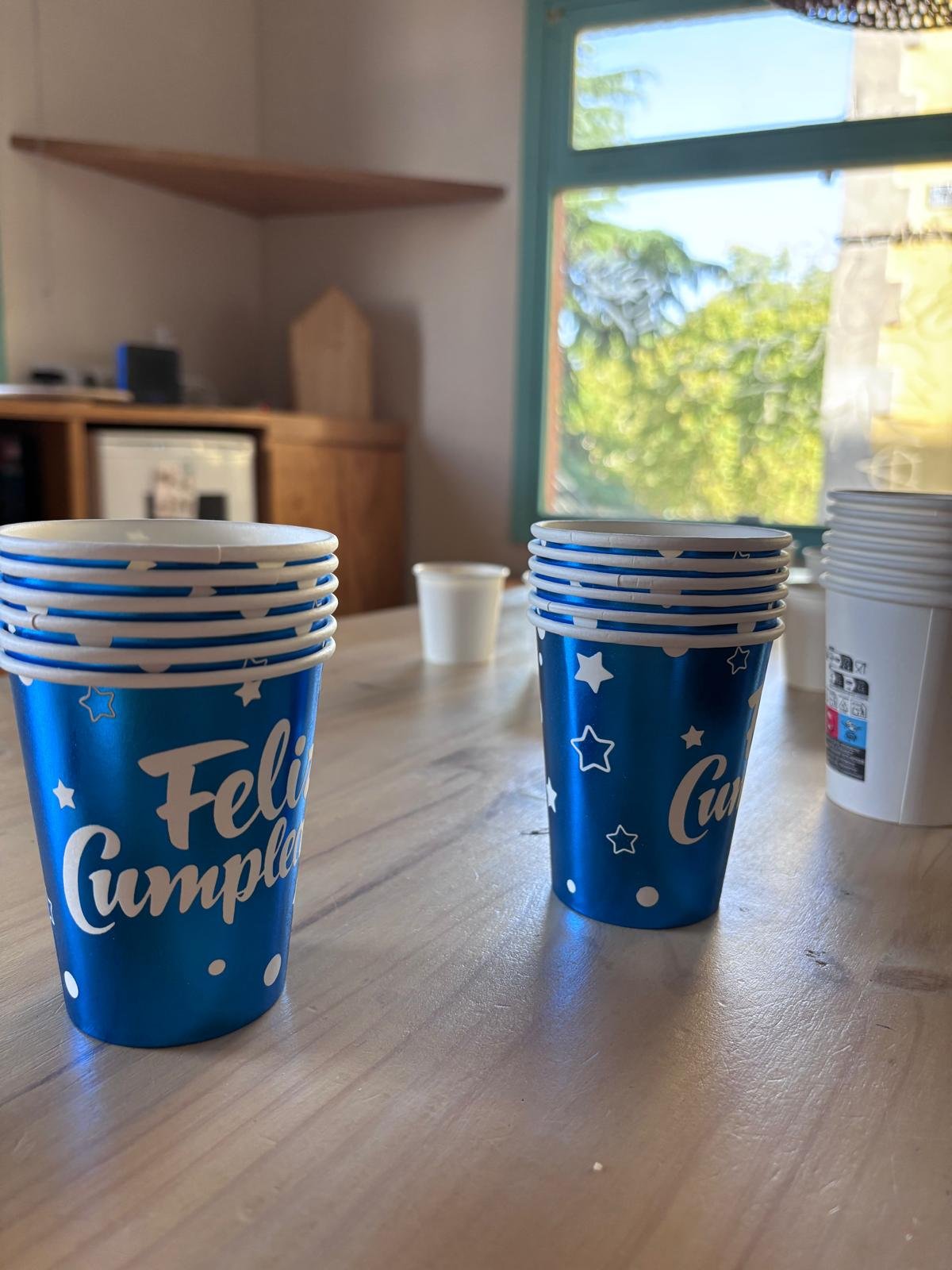 Vasos azules de Feliz cumpleaños apilados sobre la mesa