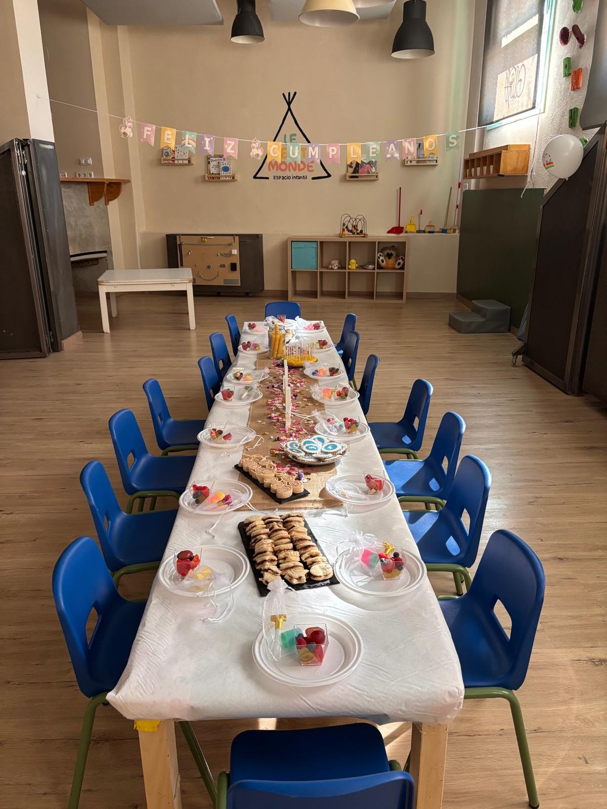 Mesa larga con sillas azules preparada para la merienda de cumpleaños